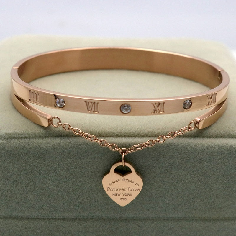 Delight in this timeless classic a Hanging Heart Label Forever Love Bracelet! Crafted of gleaming stainless steel, its Heart shape/pattern and bangle design add exquisite beauty to any look. An ideal accessory for any woman!