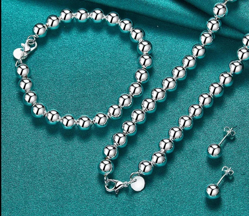 This set of jewelry includes a bracelet, necklace, and earrings made of 925 sterling silver. The beads are hollow and have a diameter of 8mm. It is designed for women and can be worn for various occasions such as weddings, engagements, or as a charm jewelry.